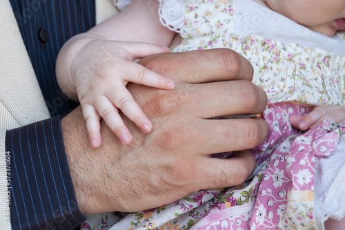 un bebé posa su mano sobre la mano de su padre.