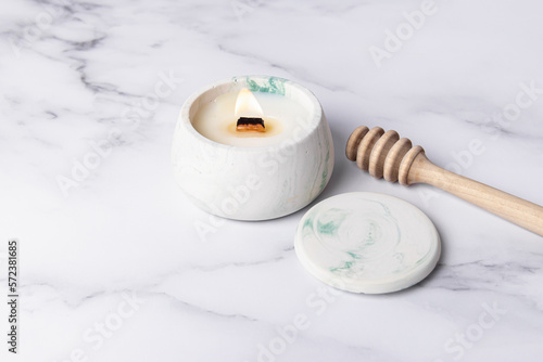 Coconut or soy wax candle in concrete cup and wooden honey spoon. Honey-scented candle. Soft focus