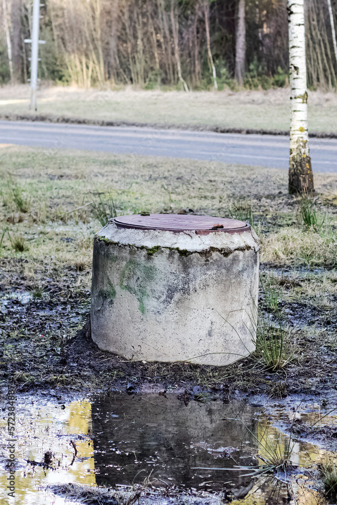 Old well in a puddle by the road Old well in a puddle by the road