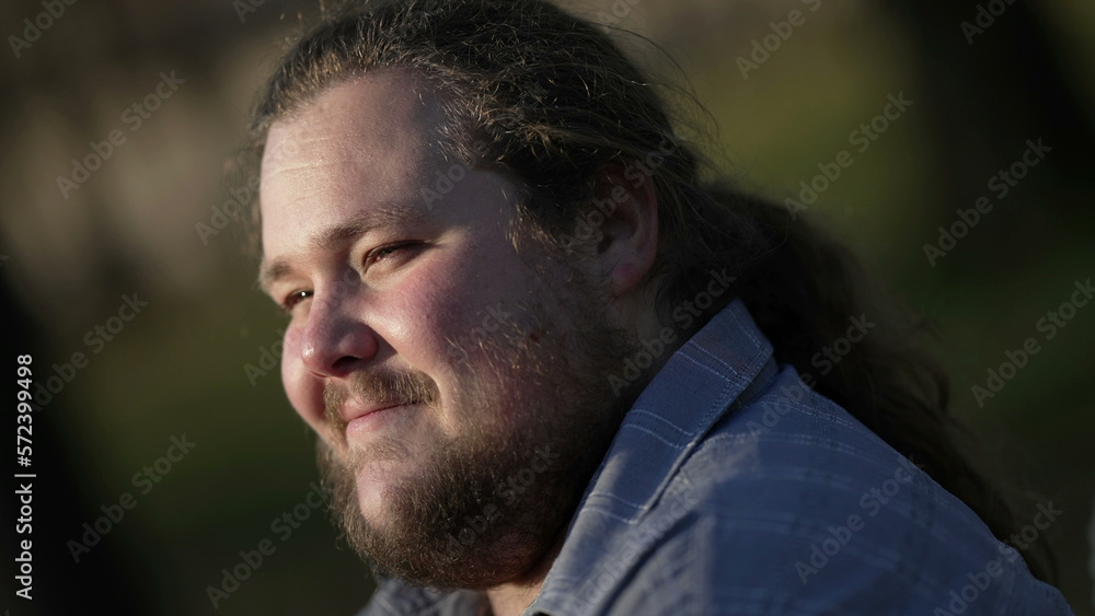 Relaxed young man sitting at park in nature feeling happy. Contemplative person smiling Relaxed young man sitting at park in nature feeling happy. Contemplative person smiling