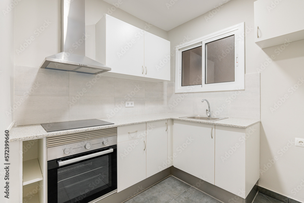 Light compact kitchen with stove, extractor hood and sink and window. Concept of kitchen in a small apartment. Modern minimalist design in new buildings Light compact kitchen with stove, extractor hood and sink and window. Concept of kitchen in a small apartment. Modern minimalist design in new buildings