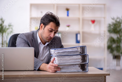 Young male employee and too much work in the office