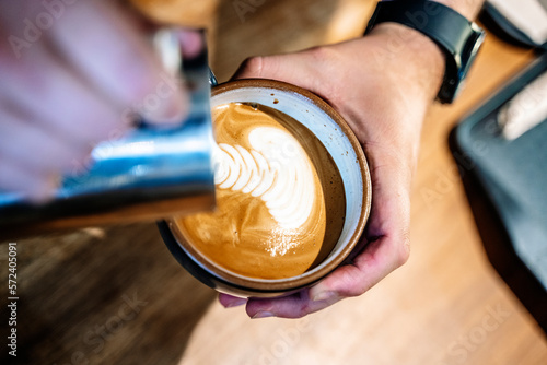 Barista makes coffee in a coffeeshop. Cup of cappuccino or latte in the making. Selected focus photo