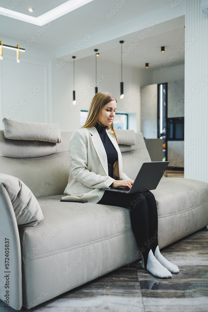 Woman cheerful charming person sitting behind a netbook watching having a good mood working at home indoors. Remote freelance work Woman cheerful charming person sitting behind a netbook watching having a good mood working at home indoors. Remote freelance work