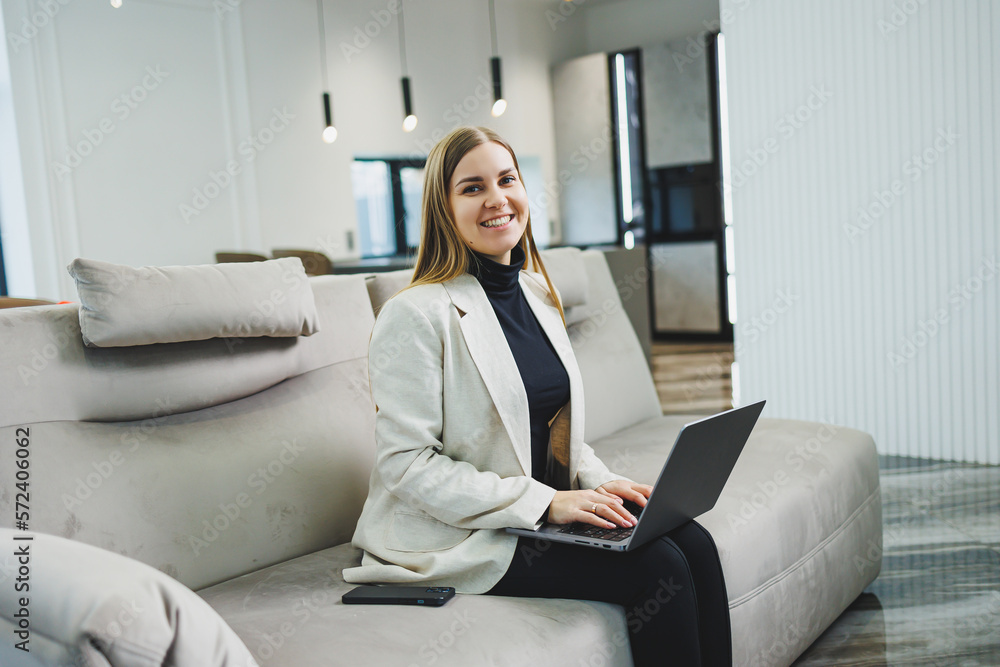 Woman cheerful charming person sitting behind a netbook watching having a good mood working at home indoors. Remote freelance work Woman cheerful charming person sitting behind a netbook watching having a good mood working at home indoors. Remote freelance work