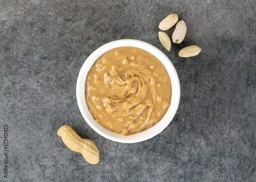 Crispy peanut butter in a bowl and peanuts on a gray background. Top view. American food.