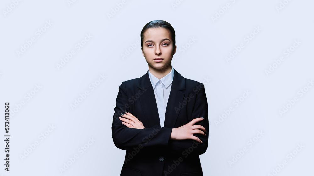 Serious teenage female student in black suit looking at camera on white background Serious teenage female student in black suit looking at camera on white background