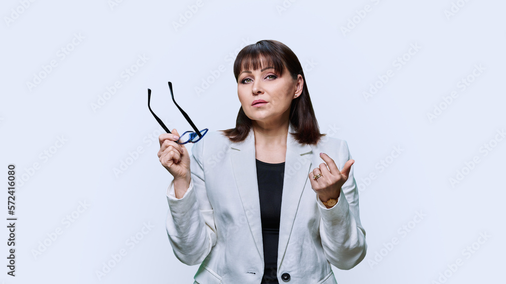 Serious business woman looking at camera holding glasses in hands on white background Serious business woman looking at camera holding glasses in hands on white background