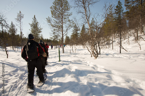 Unrecognizable group of people walking in a row with snow rackets.