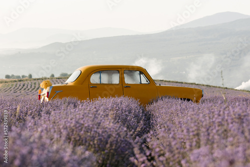 Fototapeta Naklejka Na Ścianę i Meble -  Yellow retro car in a lavender field in the morning with fog and sun.