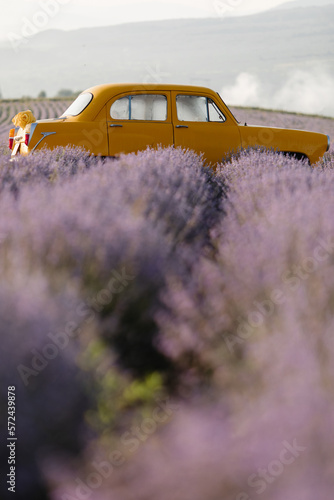 Fototapeta Naklejka Na Ścianę i Meble -  Vertical banner with a yellow retro car in a lavender field