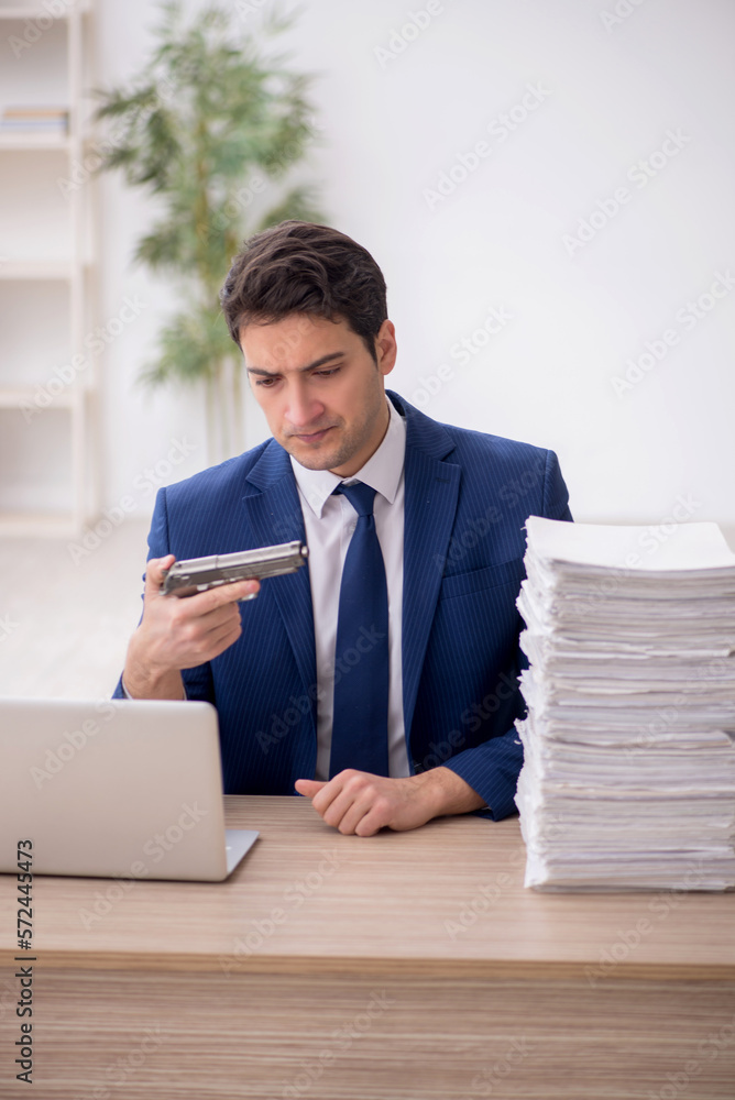 Young male employee unhappy with excessive work in the office Young male employee unhappy with excessive work in the office