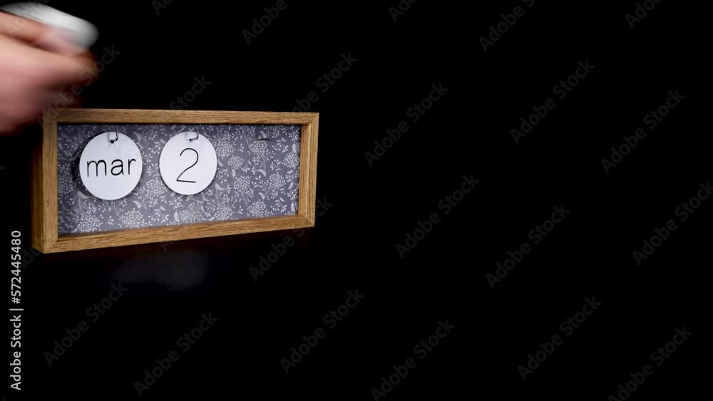 A wooden calendar block showing the date March 23rd with a mans hand putting on and taking off the metal discs with the date and month on them, filmed in 4k quality A wooden calendar block showing the date March 23rd with a mans hand putting on and taking off the metal discs with the date and month on them, filmed in 4k quality