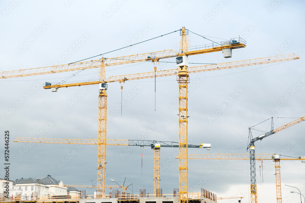 Construction site with yellow cranes on a cloudy day. Development area