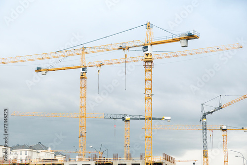 Construction site with yellow cranes on a cloudy day. Development area