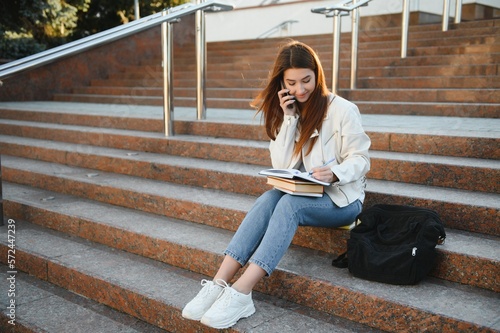 Cheerful attractive young woman with backpack and notebooks standing and smiling.