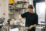 A woman cook works in a modern industrial kitchen. The process of making cakes in a bakery or cafe.