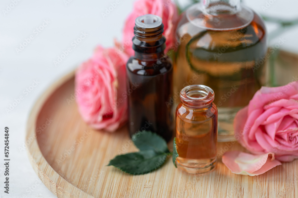 Aromatherapy. Concept of pure organic essential rose oil. Elixir with plant based floral or herbal ingredients. Pink flowers extract. Spa atmosphere with candle, towel. White background Aromatherapy. Concept of pure organic essential rose oil. Elixir with plant based floral or herbal ingredients. Pink flowers extract. Spa atmosphere with candle, towel. White background