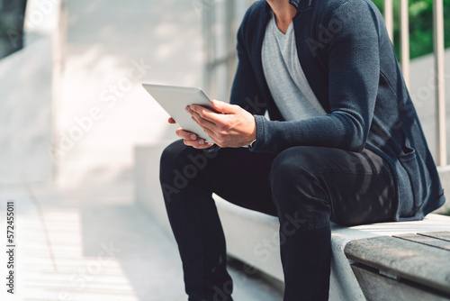 Unrecognizable man holding a digital tablet, sitting outside on a sunny day © VisualProduction