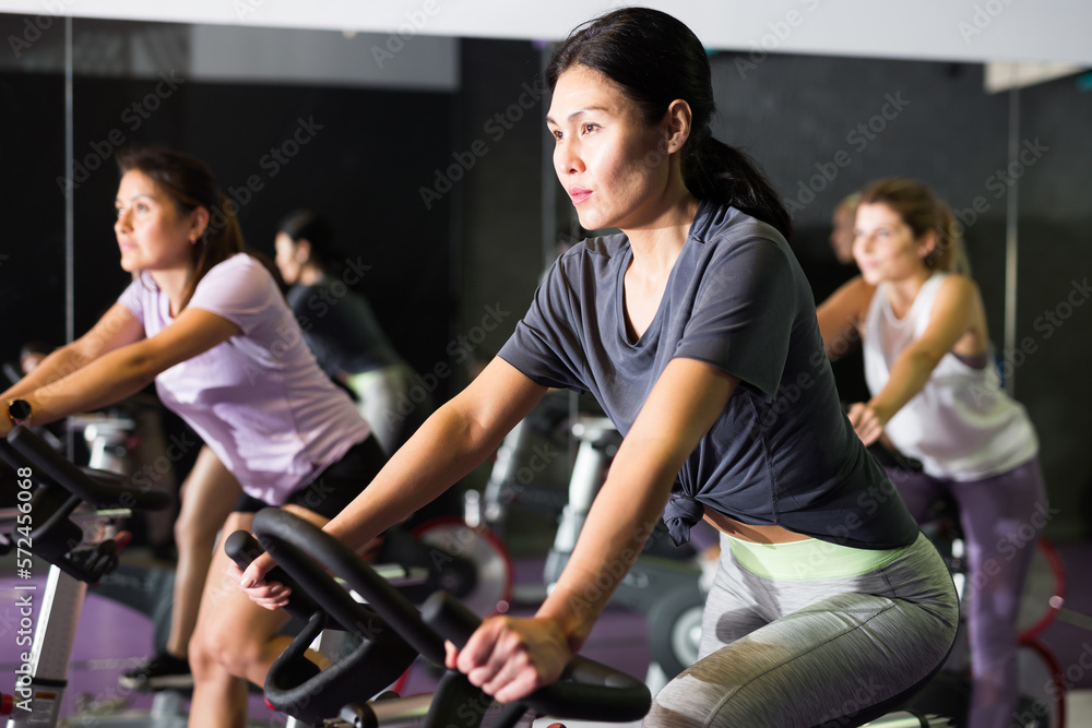 Portrait of woman doing cardio workout cycling bikes at fitness center