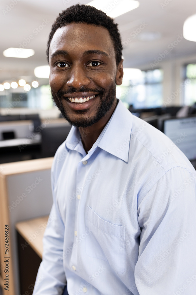 Vertical image of happy african american businessman looking at camera in office Vertical image of happy african american businessman looking at camera in office