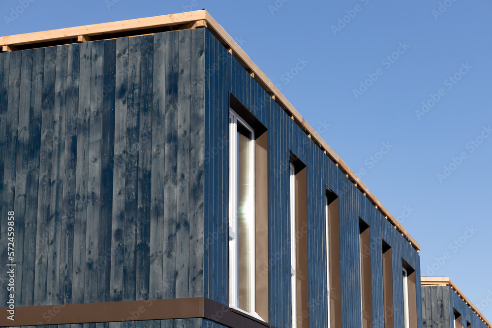  Wooden facade of a separate modular house with windows. Close-up