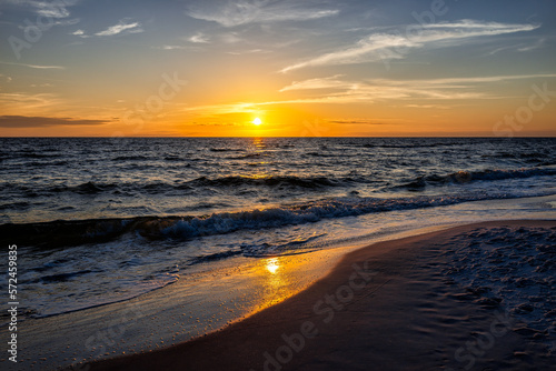 Colorful sunset dusk with seascape horizon of sun setting in Gulf of Mexico sea ocean coast with water waves in Seaside Santa Rosa Beach, Florida panhandle and reflection of path