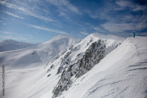 Fototapeta Naklejka Na Ścianę i Meble -  An alpinist climbing a rocky and snow mountain ridge