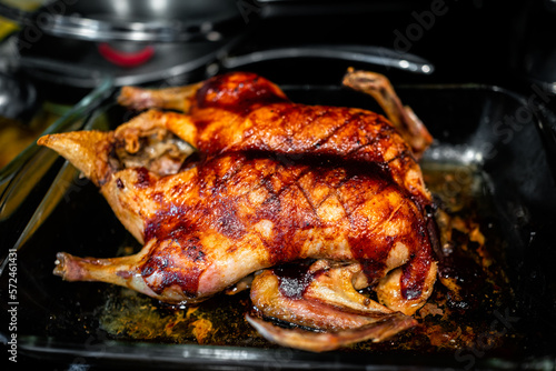 Whole roasted duck poultry bird closeup macro with score marks on in glass pan for baking with crispy brown golden skin texture