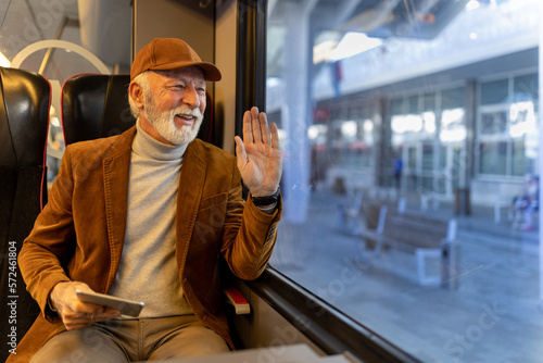 Man traveling in train and waving hand at station photo