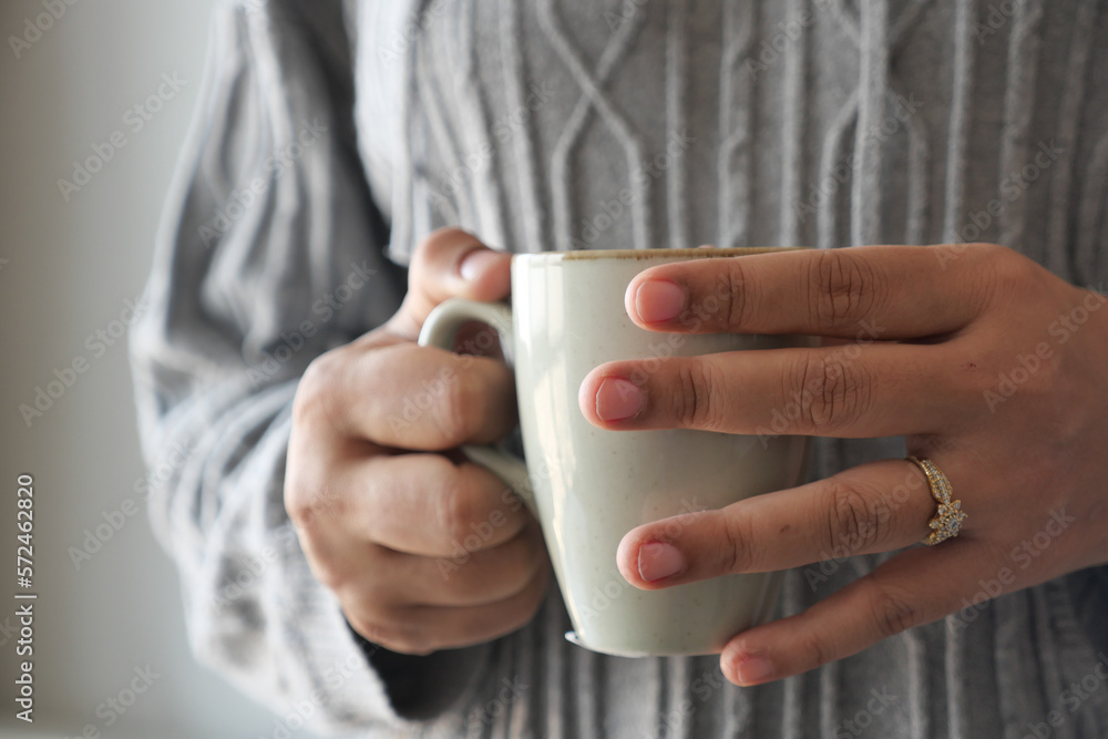 Close up of women's hand holding coffee mug Close up of women's hand holding coffee mug