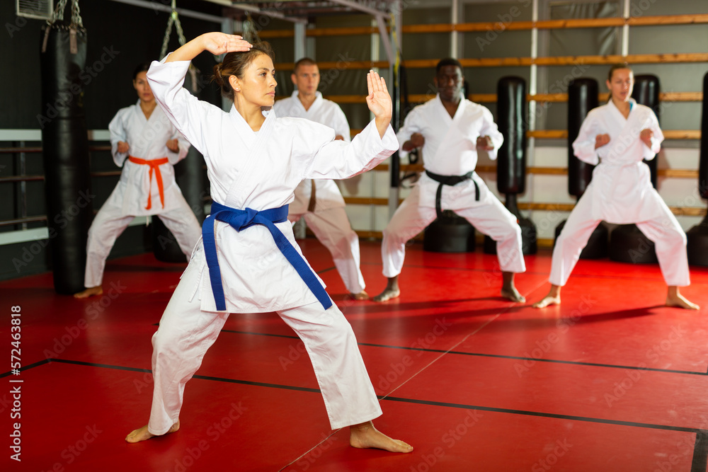 Fototapeta premium Woman in kimono fighting stance at karate training
