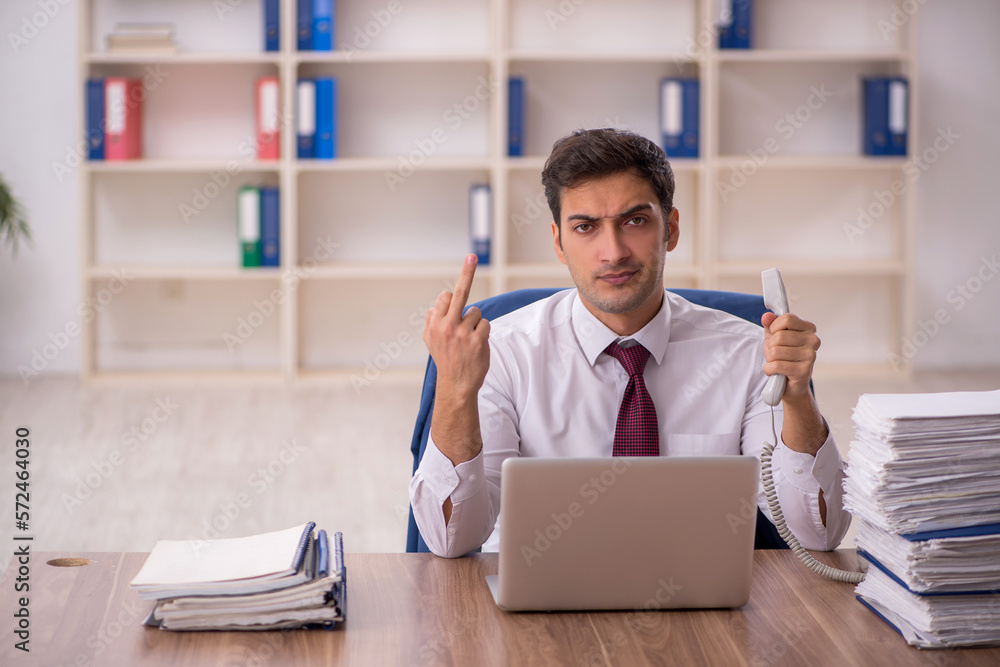 Young male employee and too much work in the office Young male employee and too much work in the office