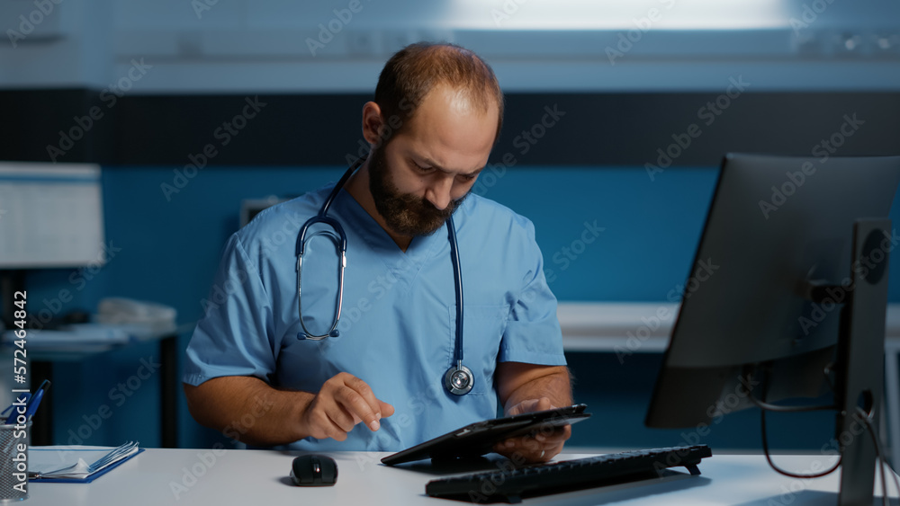 Physician man assistant holding tablet computer typing medical expertise in hospital office. General practitioner nurse working late at night at patient health care treatment.