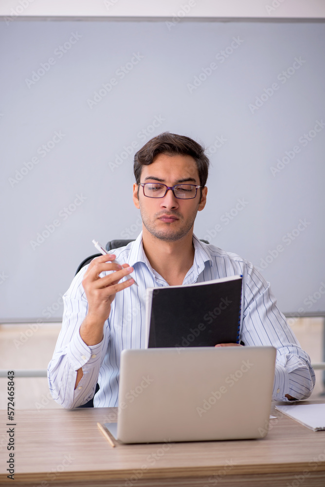Young male teacher sitting in the classroom Young male teacher sitting in the classroom