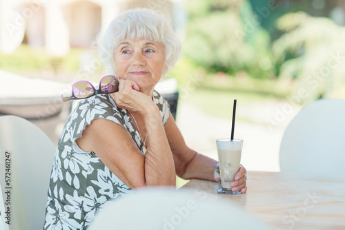 Photography Portrait of attractive senior woman sitting in a summer outdoor cafe and drinkin