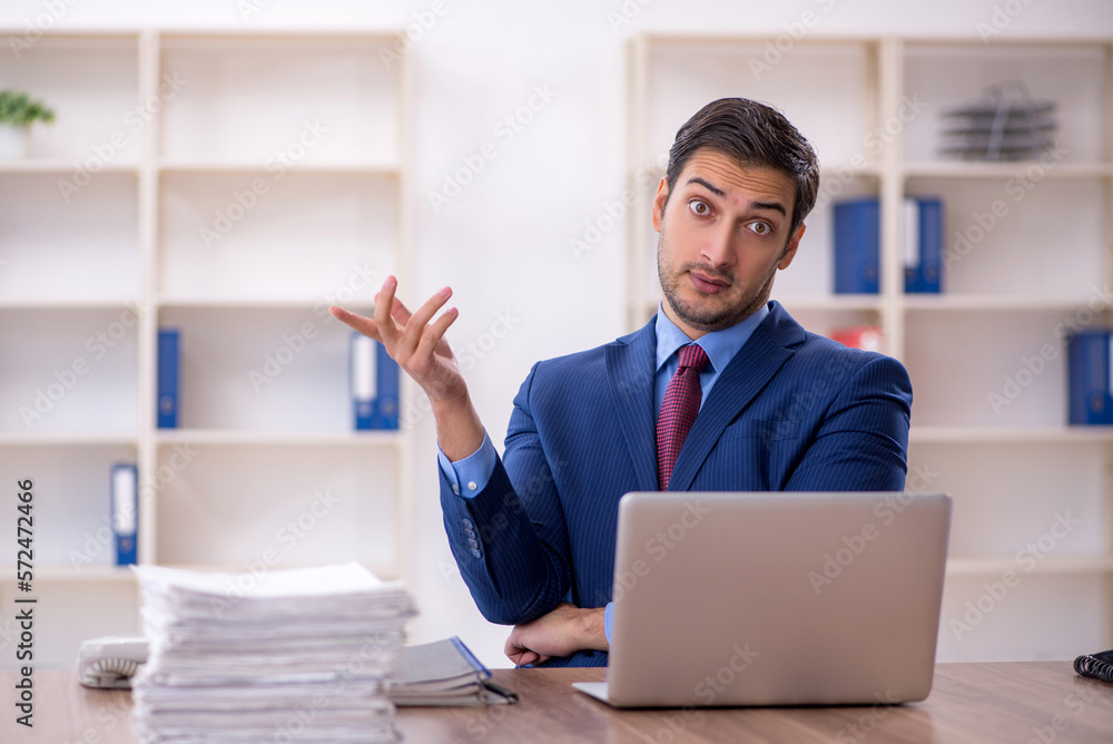 Young male employee and too much work in the office Young male employee and too much work in the office