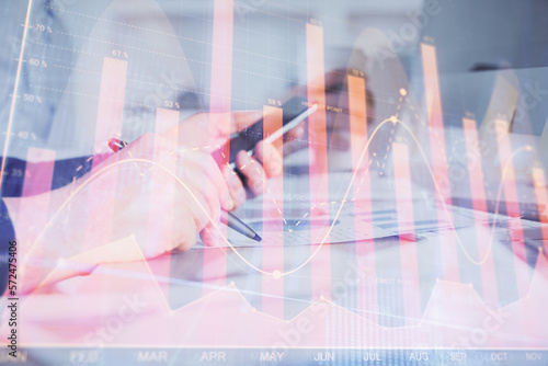 Double exposure of man's hands holding and using a phone and financial chart drawing. Market analysis concept.