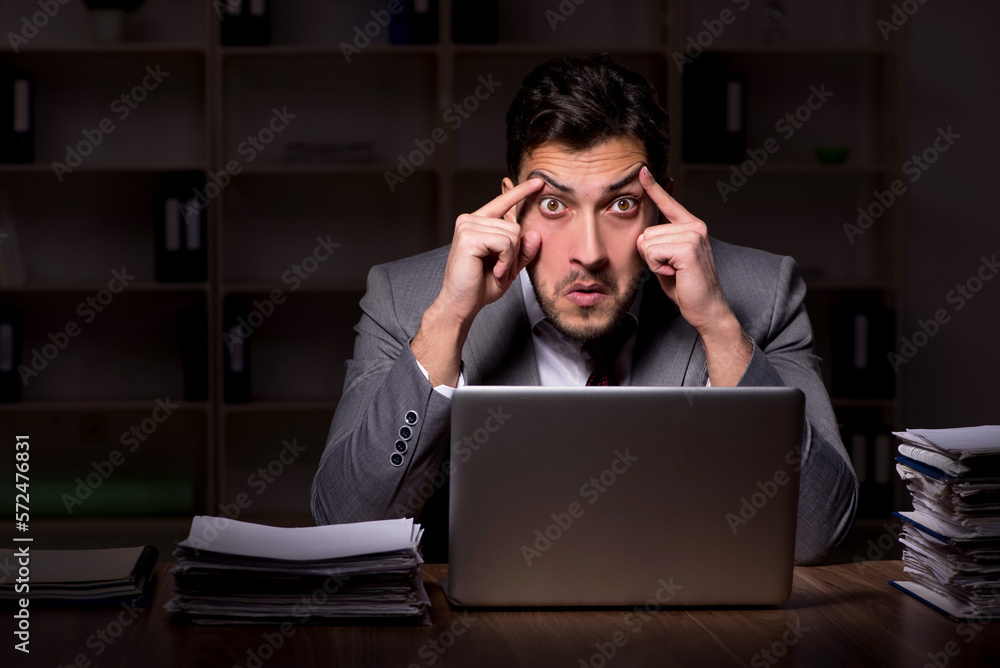 Young male employee working late in the office Young male employee working late in the office