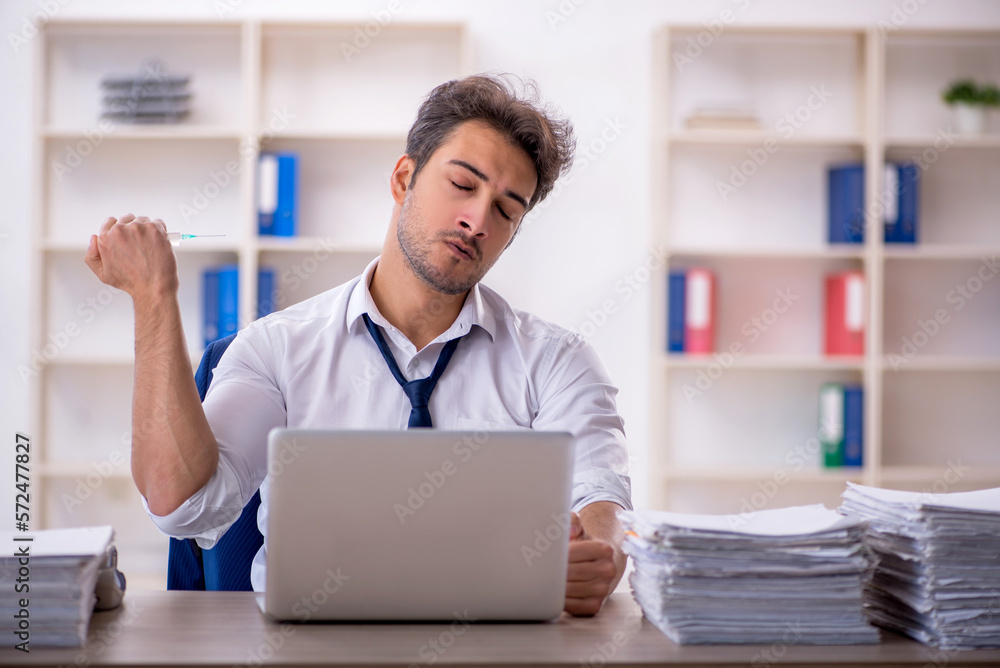 Young male employee and too much work in the office Young male employee and too much work in the office