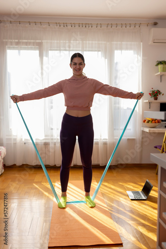 Online workout. Teen girl doing Sport exercise at home, watching tutorials on a laptop. How to keep fit indoors