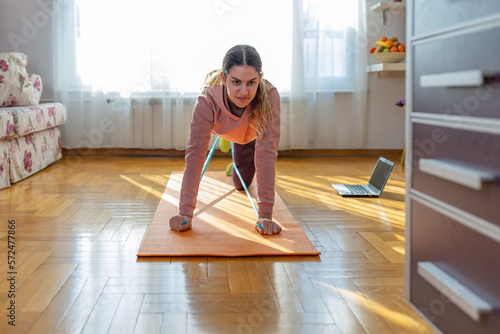 Online workout. Teen girl doing Sport exercise at home, watching tutorials on a laptop. How to keep fit indoors