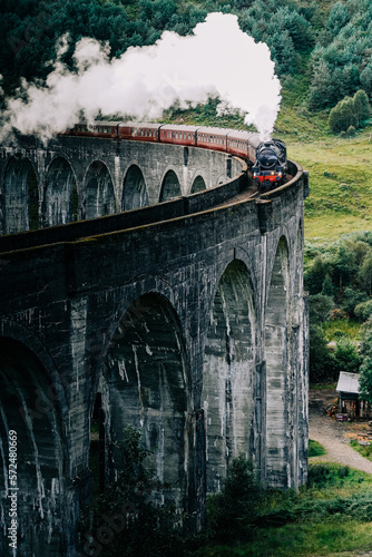 A steam train crossing the Glenfinnan viaduct in the Scottish Highlands made famous by the Harry Potter movies. The Jacobite steam train crossing the bridge with steam in Scotland United Kingdom