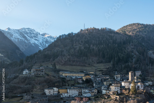 Little village of Gromo, Lombardy, Italy - February 2023. The last rays of the setting sun illuminate the village