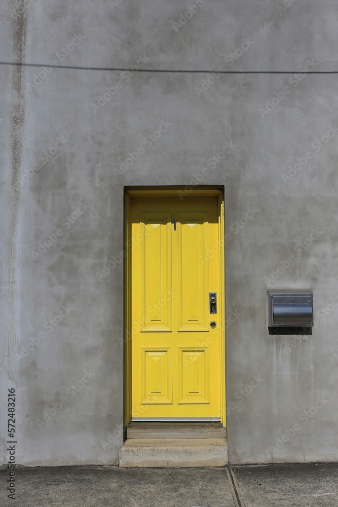 Yellow door in a plain concrete facade.