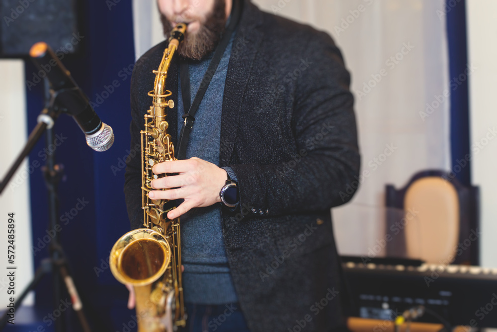 Fototapeta premium Concert view of saxophonist, a saxophone sax player with vocalist and musical band during jazz orchestra show performing music on stage in the scene lights