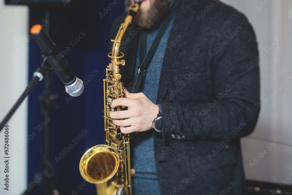 Fototapeta premium Concert view of saxophonist, a saxophone sax player with vocalist and musical band during jazz orchestra show performing music on stage in the scene lights