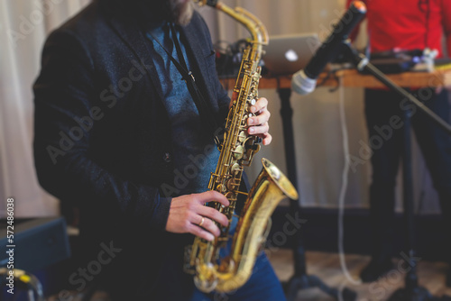 Concert view of saxophonist  a saxophone sax player with vocalist and musical band during jazz orchestra show performing music on stage in the scene lights
