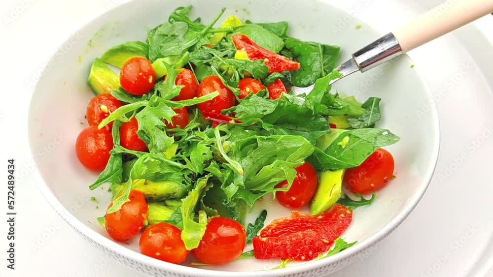a plate of fresh green salad with cabbage leaves, tomatoes, cucumber and avocado on white table a plate of fresh green salad with cabbage leaves, tomatoes, cucumber and avocado on white table
