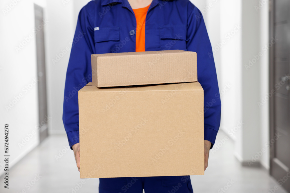 Courier with cardboard boxes in hallway, closeup Courier with cardboard boxes in hallway, closeup